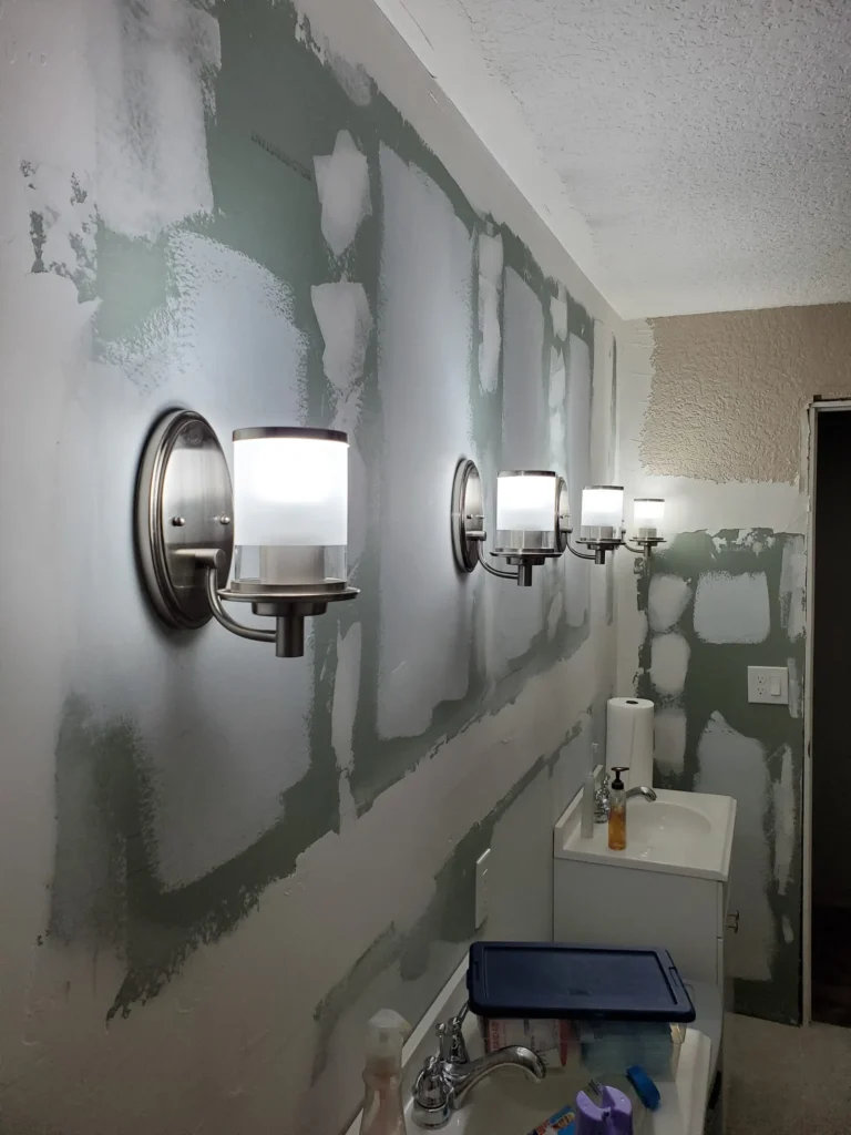 Bathroom remodeling project with newly installed vanity sconces and updated electrical lighting