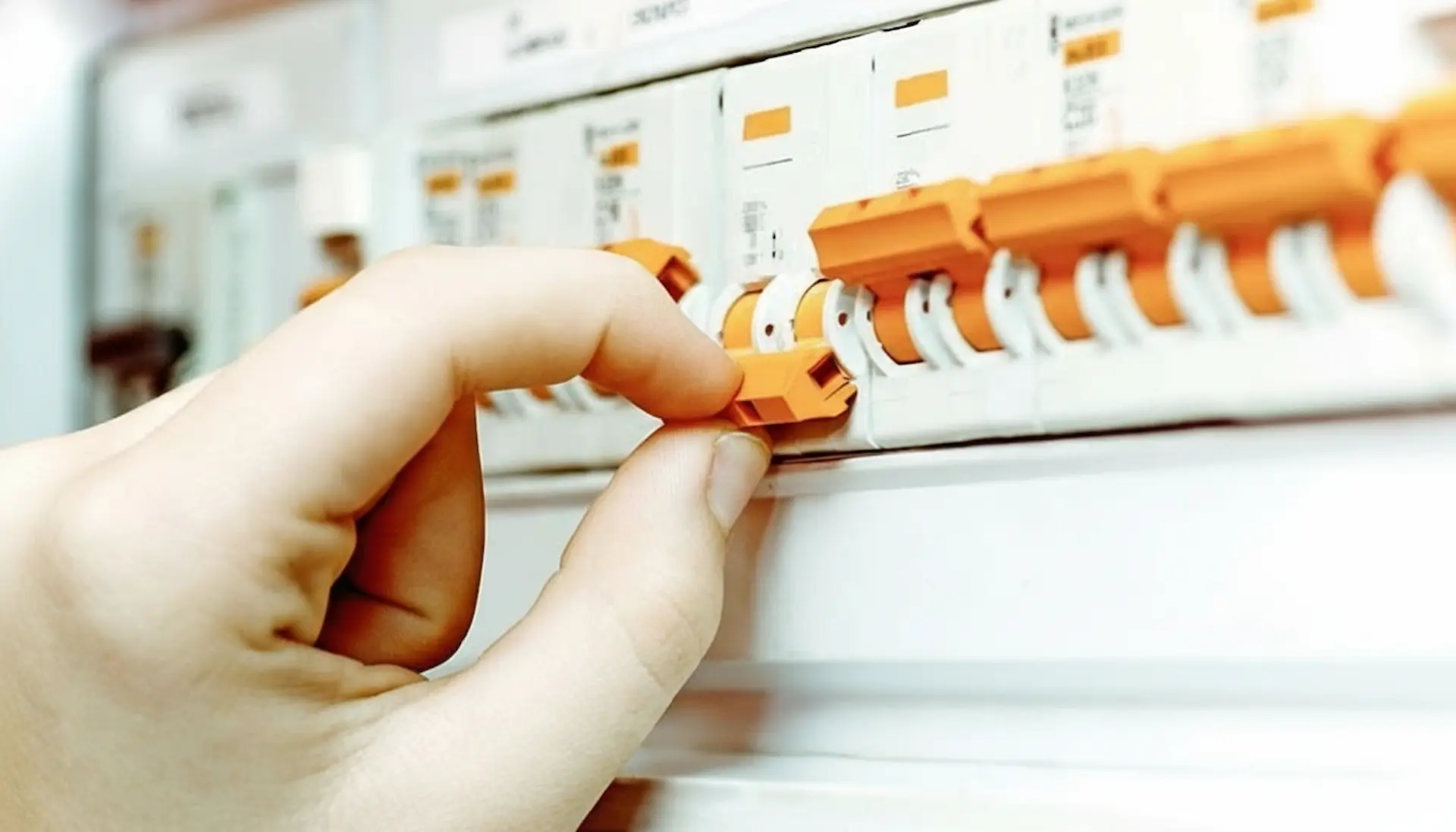 A close-up view of a hand operating a switch during a circuit breaker installation in a modern residential electrical panel.